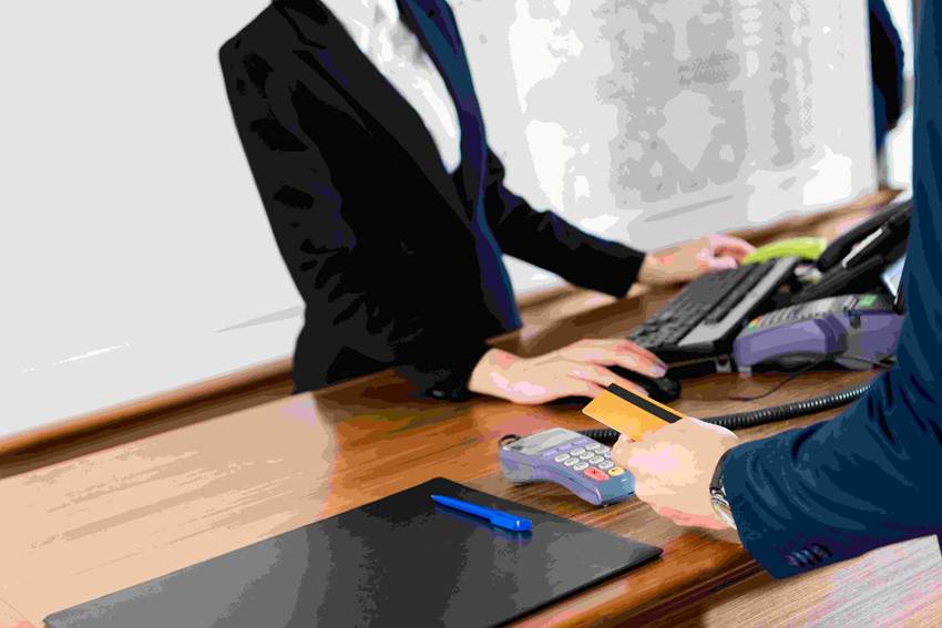 ホテルのフロントでクレジットカードで支払う男性