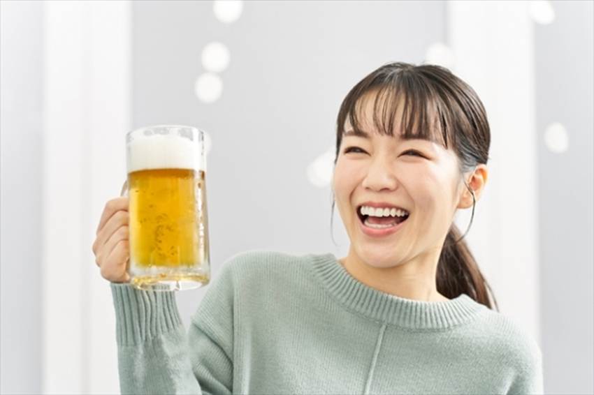 生ビールの入ったビールジョッキを、笑顔で掲げる女性