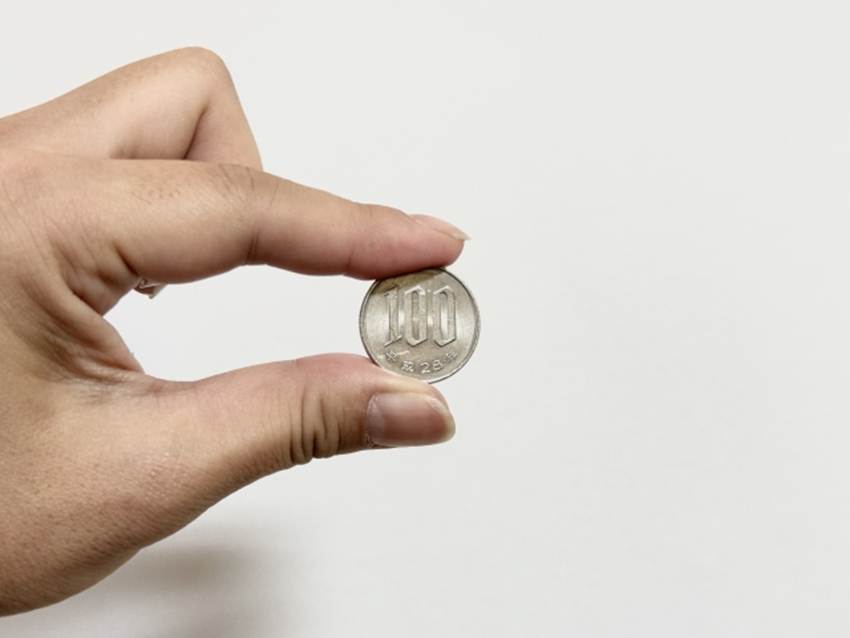 親指と人差し指でつままれている100円硬貨