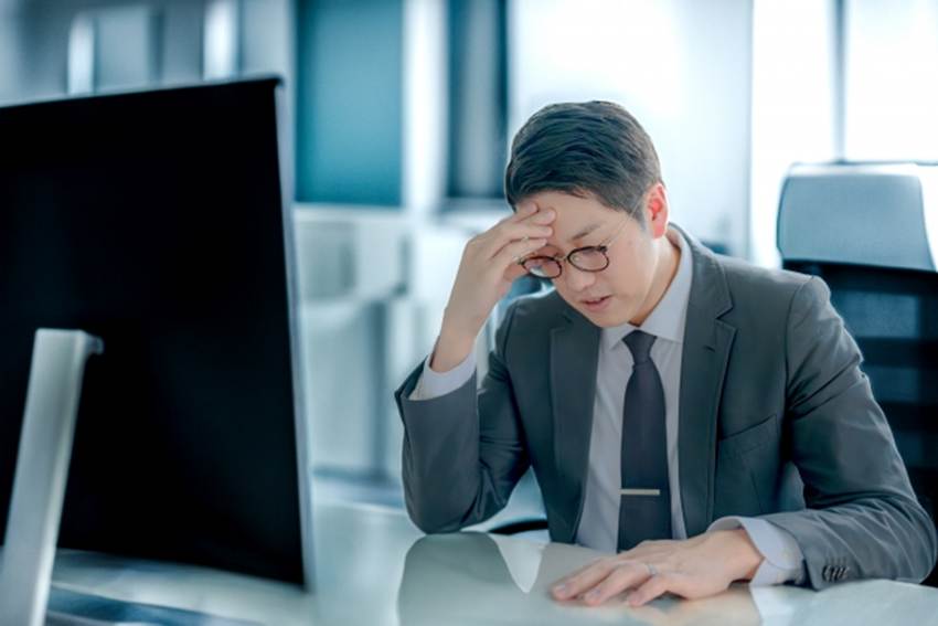 パソコンの前で頭を抱えている男性