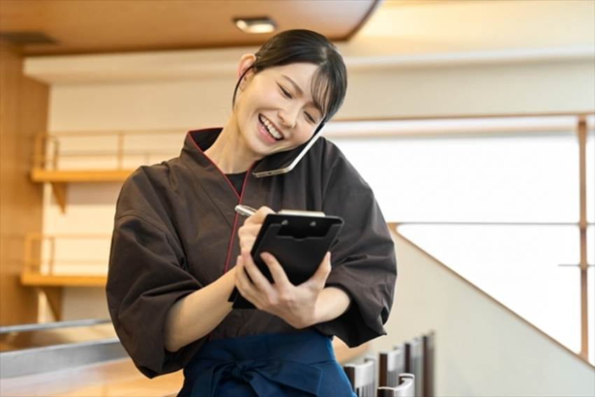 予約の受け付けをする飲食店の女性従業員
