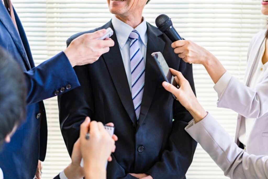 貴社に囲まれてインタビューを受ける男性