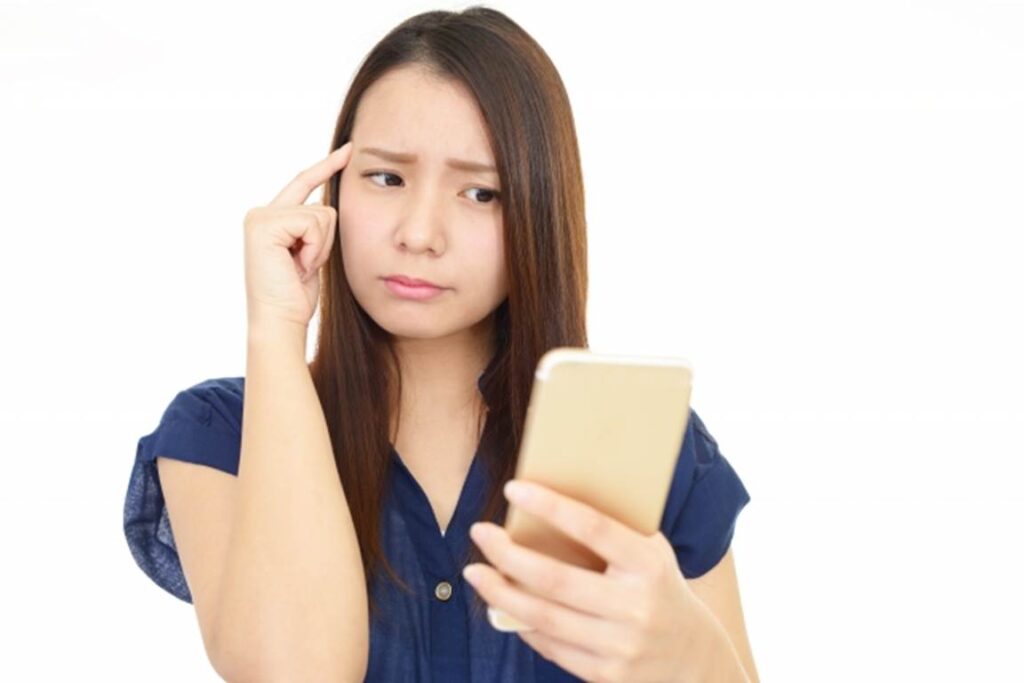 スマートフォンの画面を見ながら不安を感じる女性