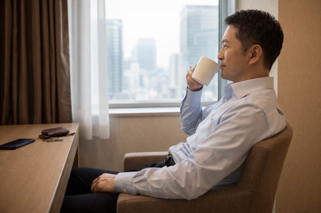 ホテルの部屋でコーヒーを飲みながら、くつろぐ男性