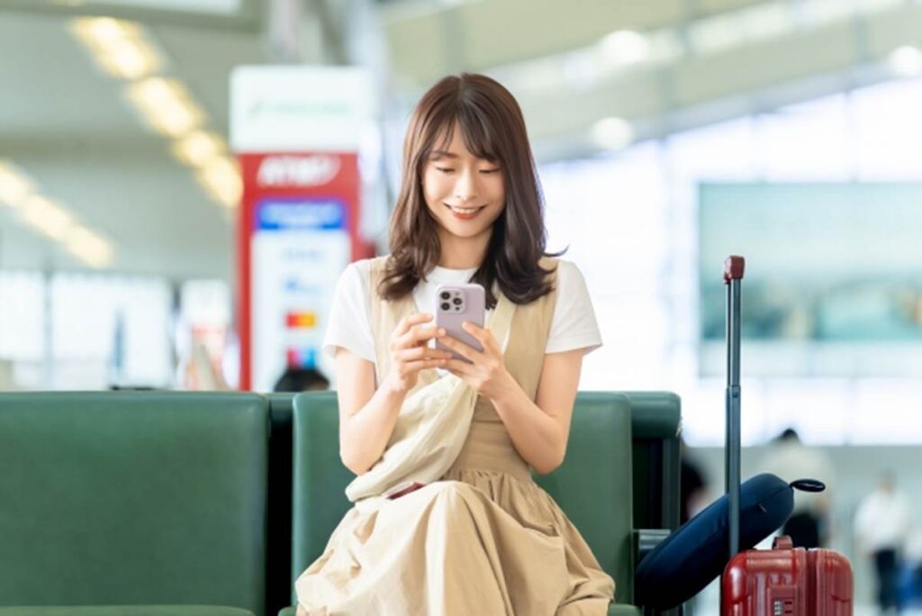 スマートフォンの画面を見る、旅行中の女性