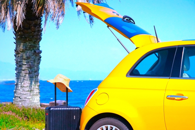 海沿いに停車している自動車とキャリーバッグ