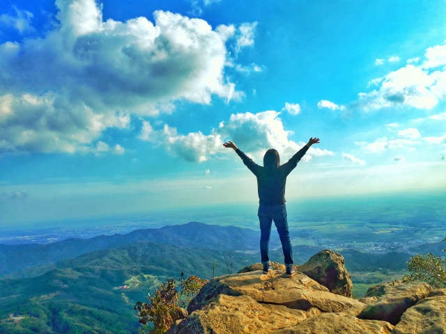 絶景を見下ろしながら手を広げる女性