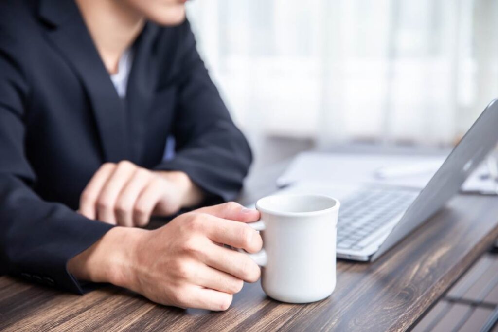 コーヒーを飲みながら、パソコンの画面を見つめる男性