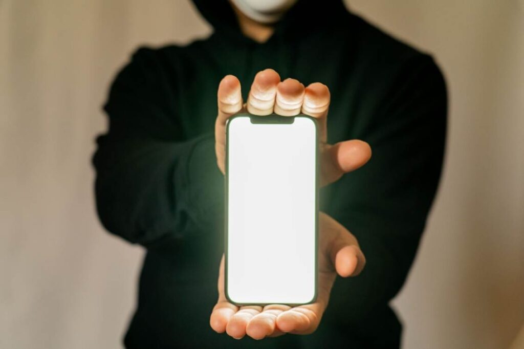 スマートフォンを両手にはさんで、画面を見せる不審な人物