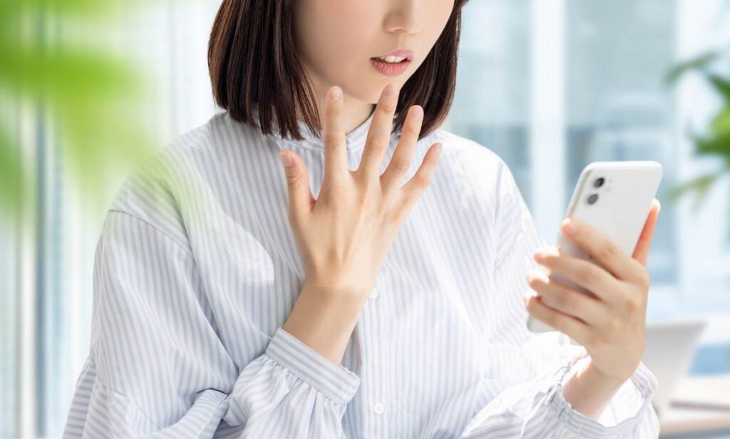 スマートフォンの画面を見て驚く女性